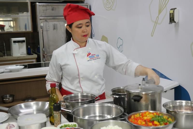 Chef Thaís Okamoto preparando prato ao vivo como personal chef